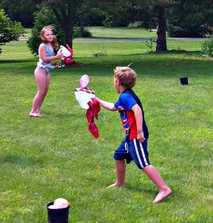 Children playing milk jug water balloon toss in the garden
