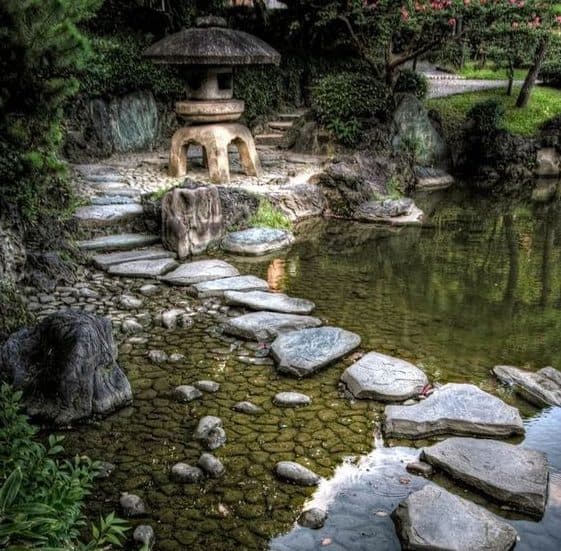 Stepping stones on river with a large stone pagoda as a focal point