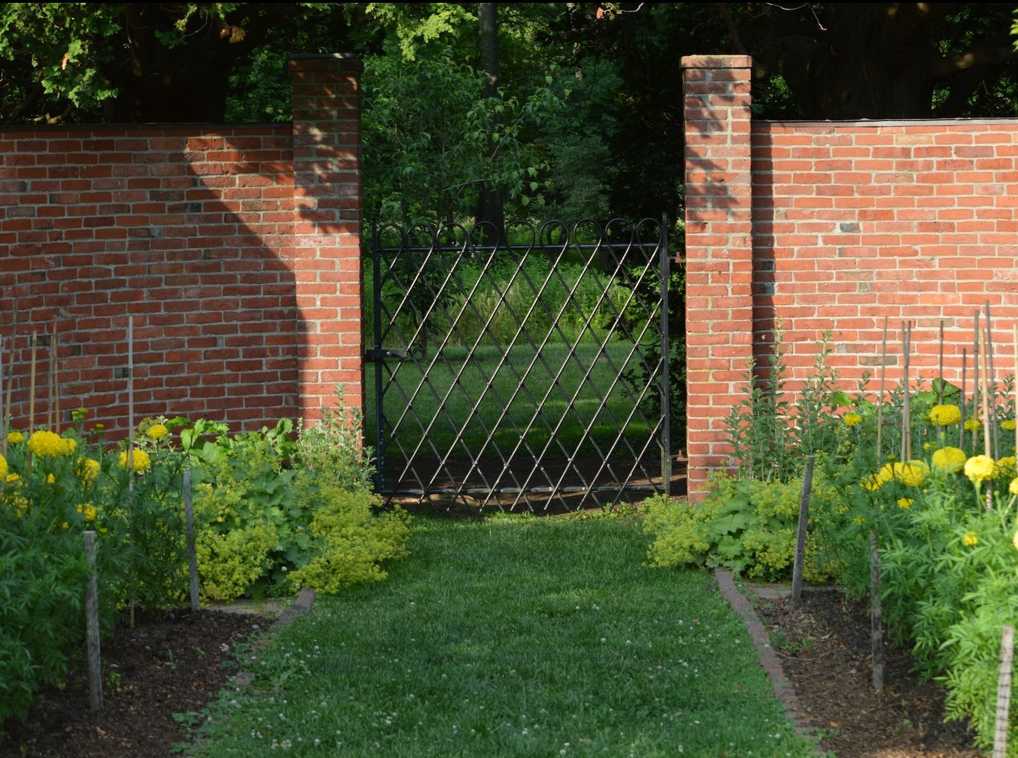 A small garden entrance with tall brick wall way to the veggie garden