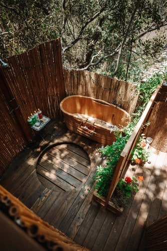 A wooden outdoor hot tub in a bamboo-theme outdoor bath