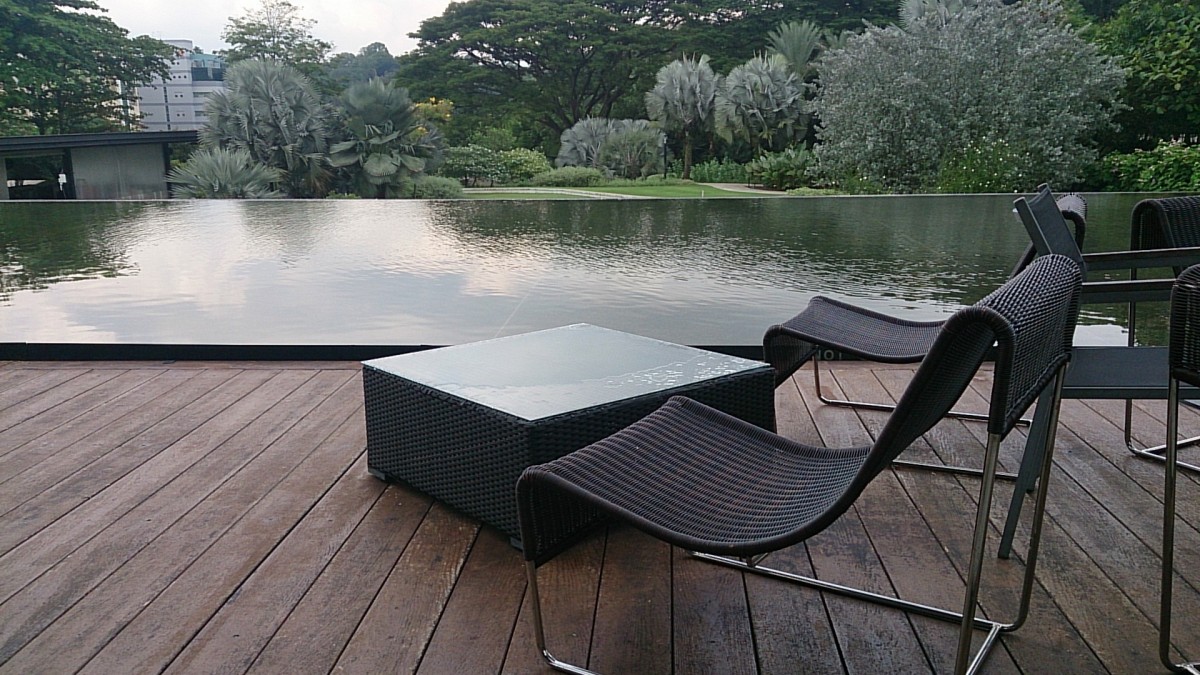 Large decking with lounger seating and a lake view