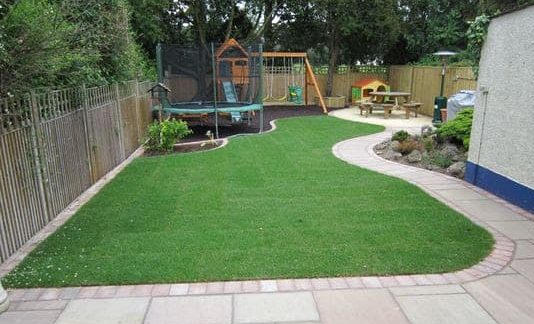 Playground in large backyard with a trampoline, swing set and Wendy house