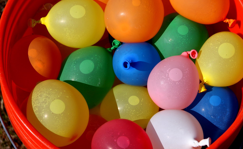 Colourful water balloons in a big red tub
