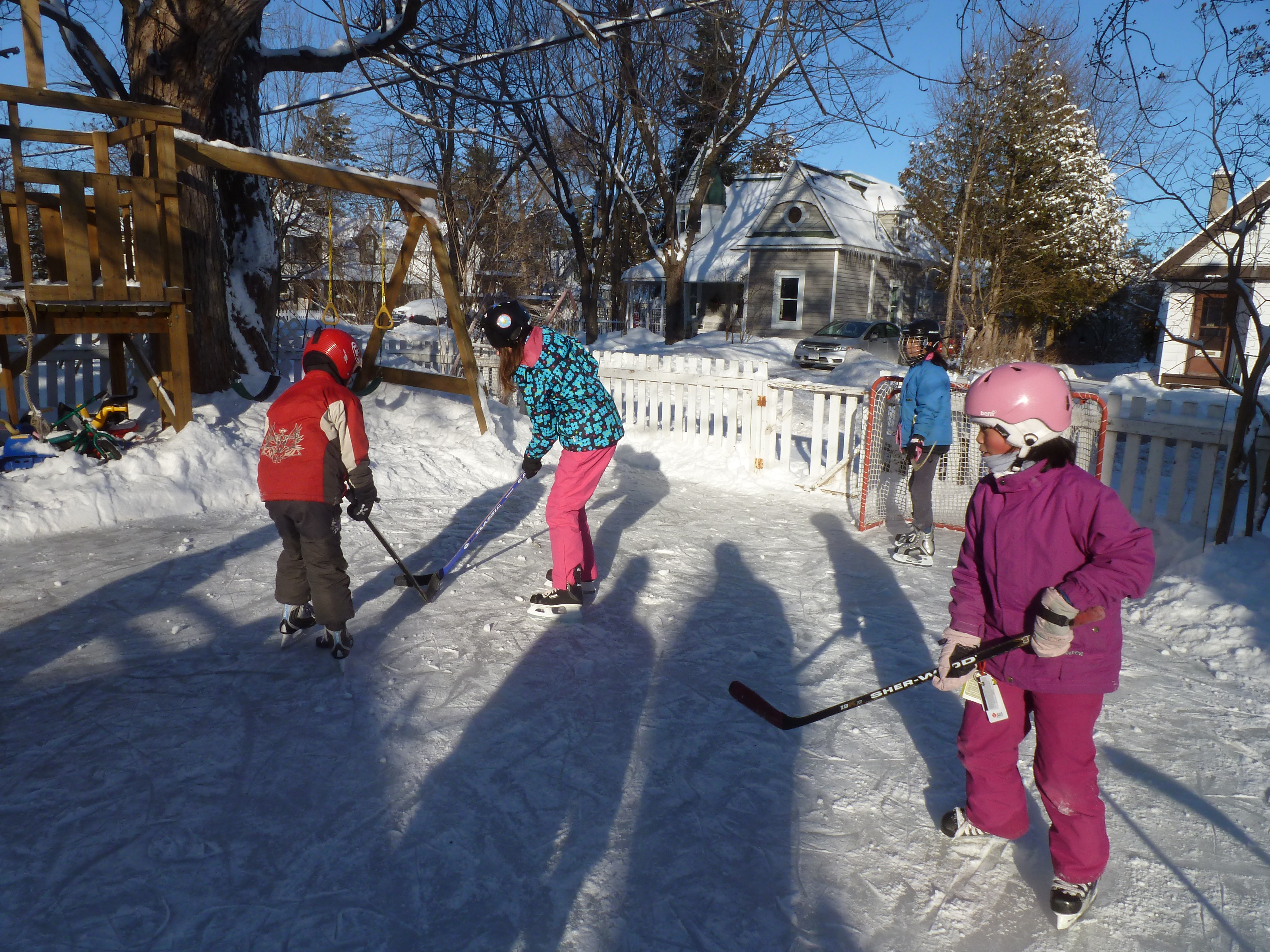Kids playing outdoor hockey on a snowy backyard