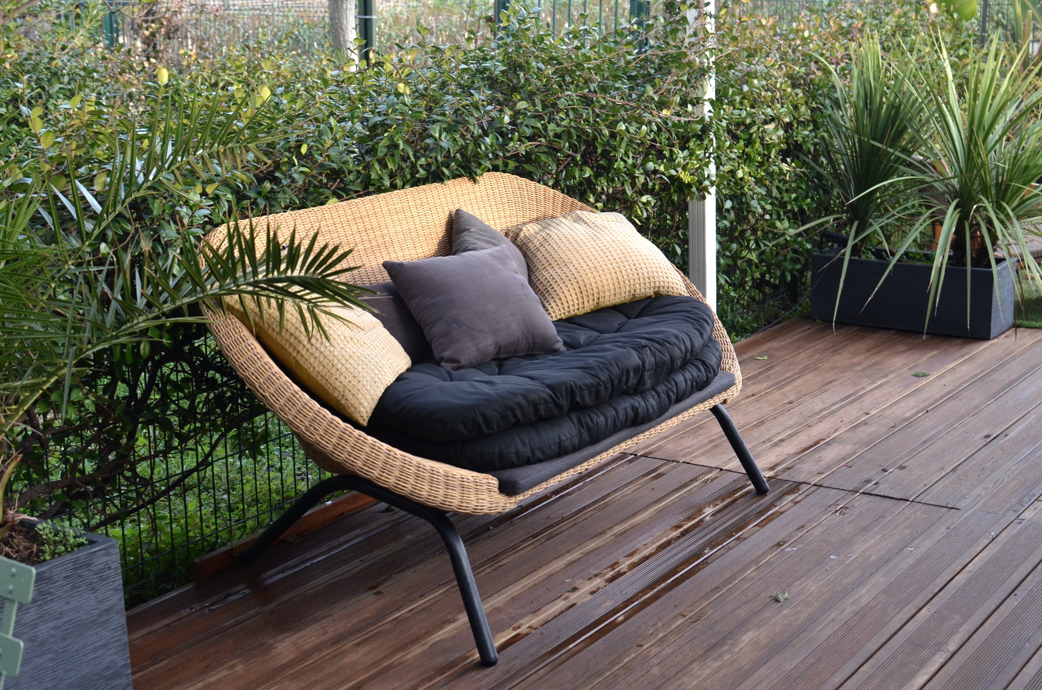 Mini woven rattan sofa on a decked patio