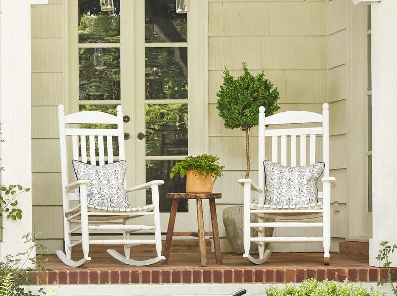 A pair of white rocking chairs placed in a front porch
