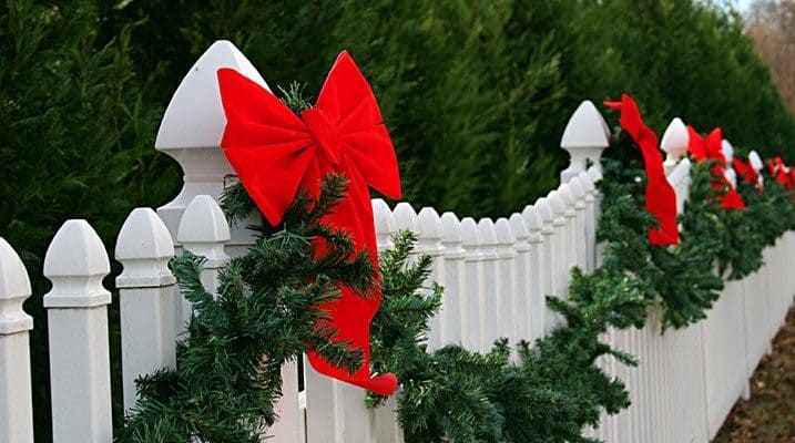 White garden fence decorated with garlands and big bows