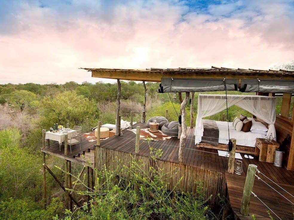 An open space treehouse sitting on a wooden deck over the African bush