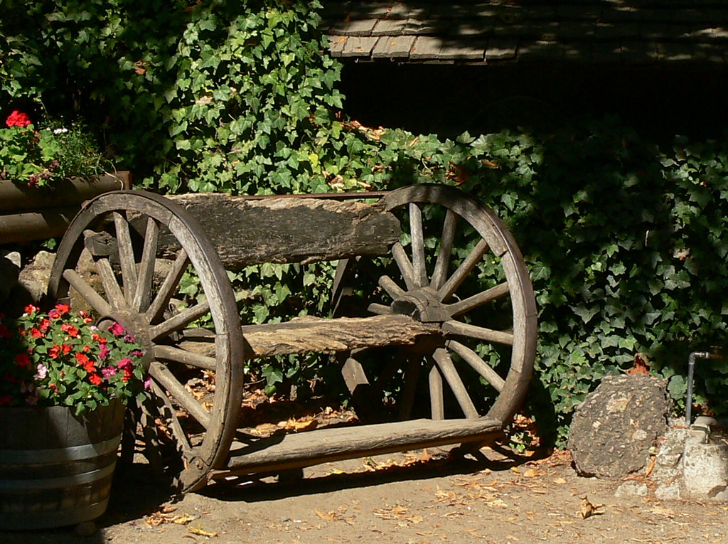 Rustic garden bench with wagon wheels as support