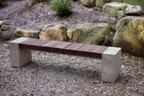 A simple garden bench made of wood, concrete, and metal materials