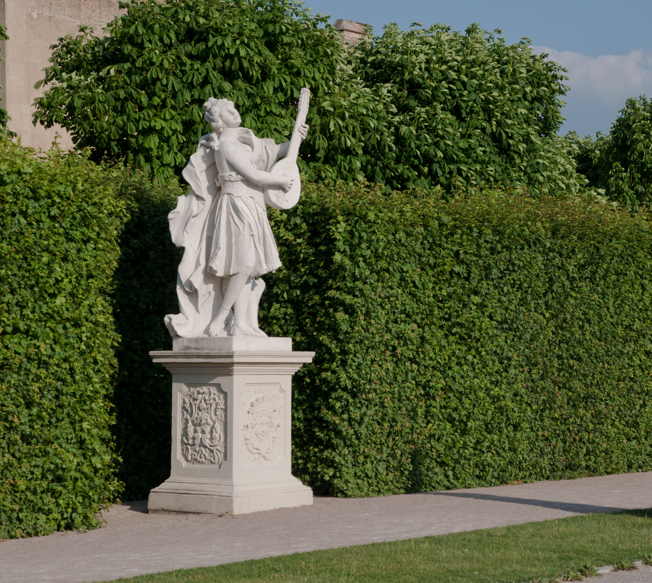A garden statue positioned amongst the wall hedges