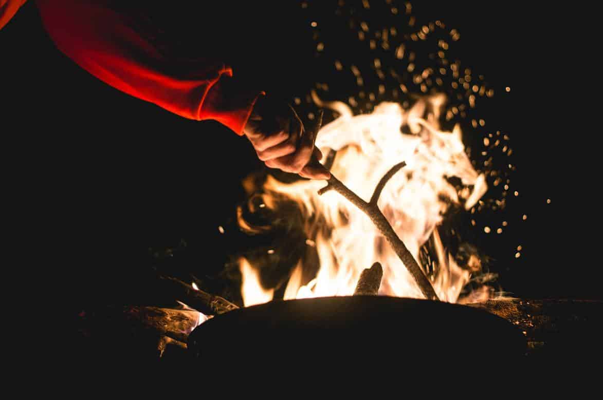 A person lighting the fire pit with sticks