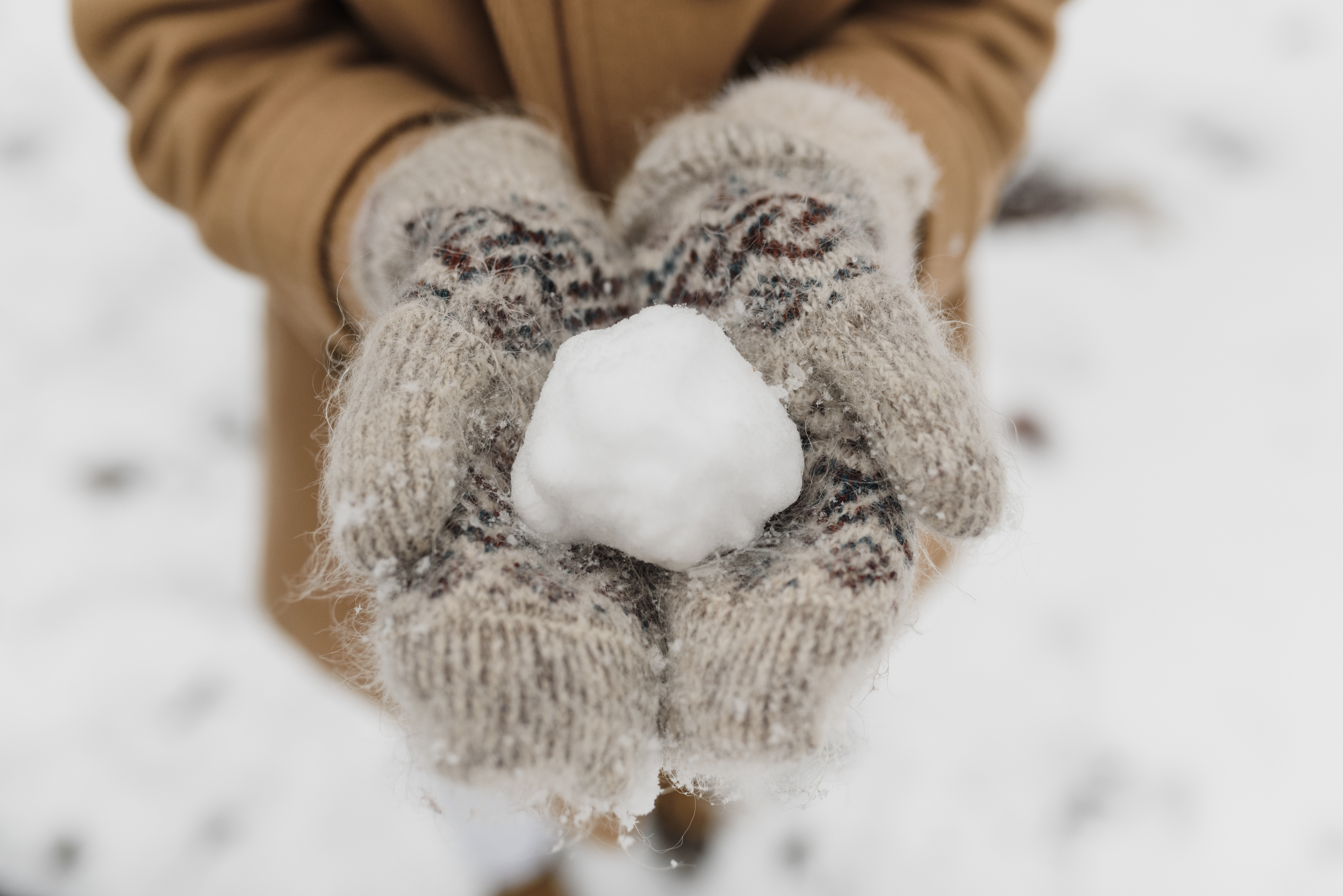 A person wearing knitted gloves holding a snow