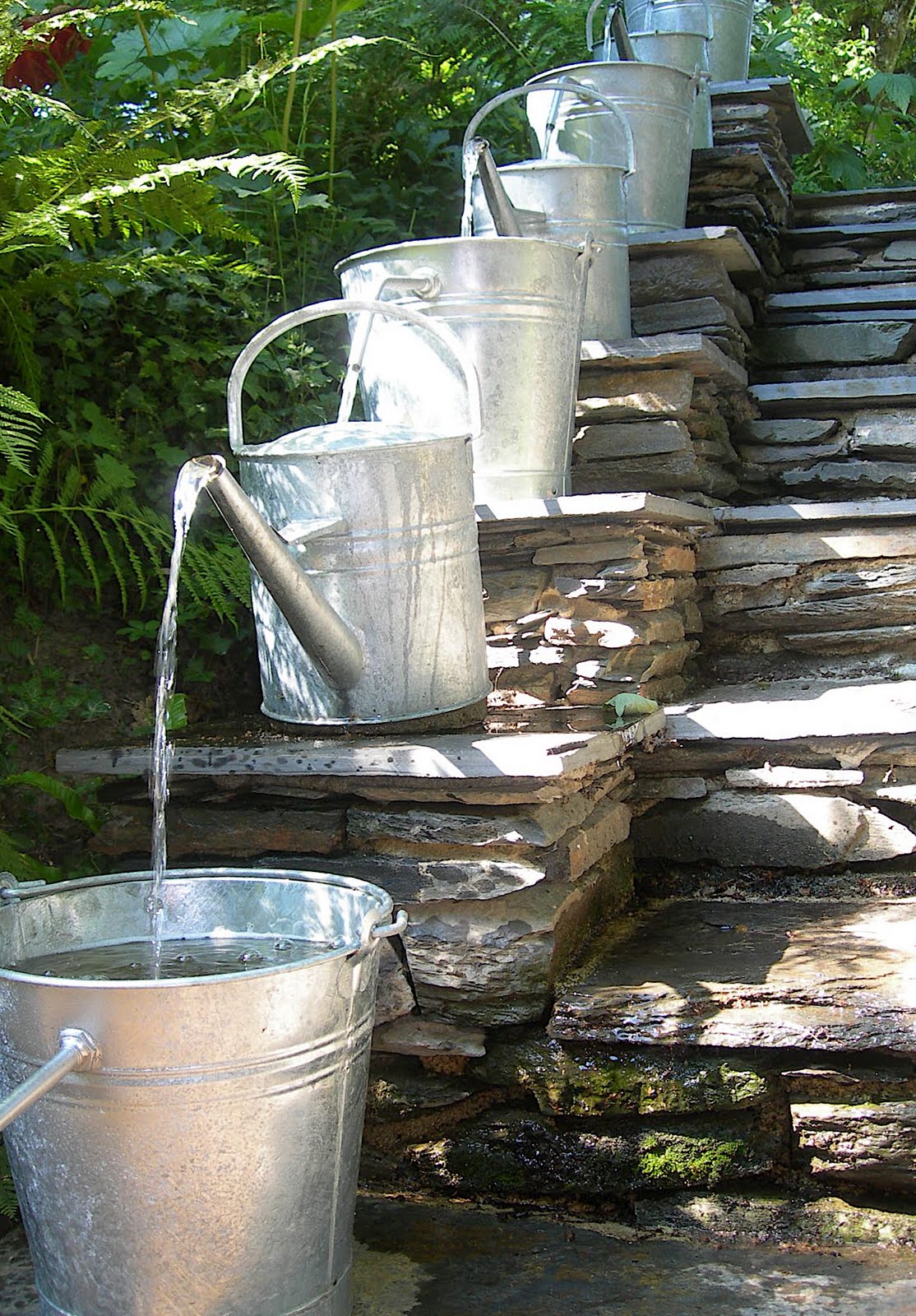 DIY sloped water feature made from watering cans