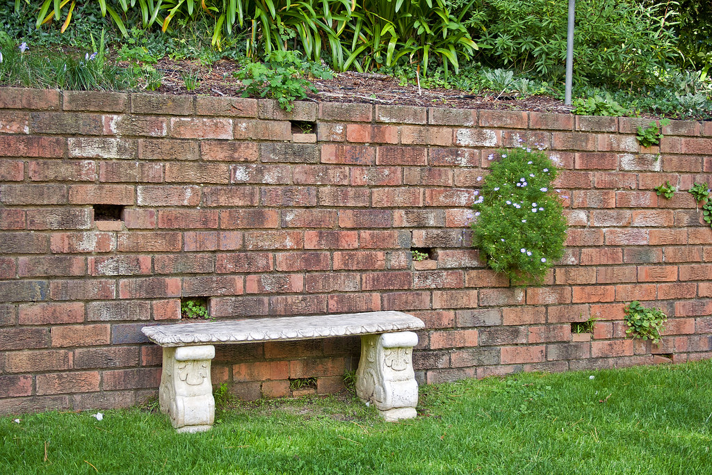 Stone garden bench positioned on a brick wall