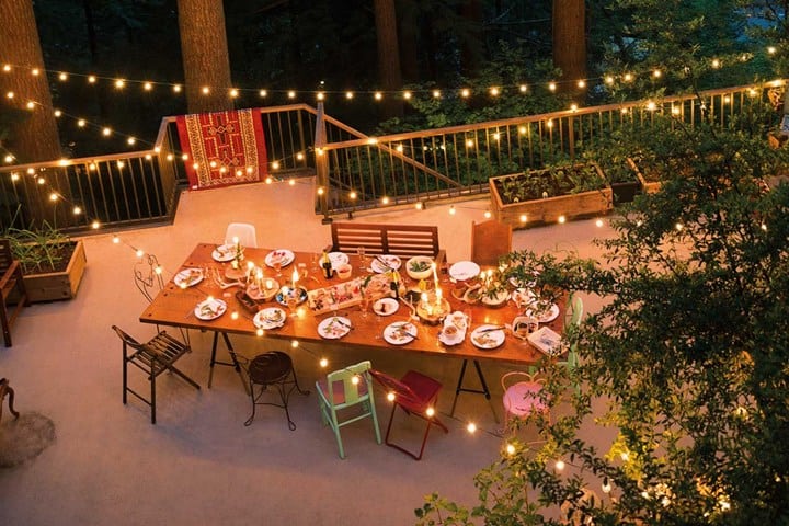 Suspended globe lights above a long outdoor dining table