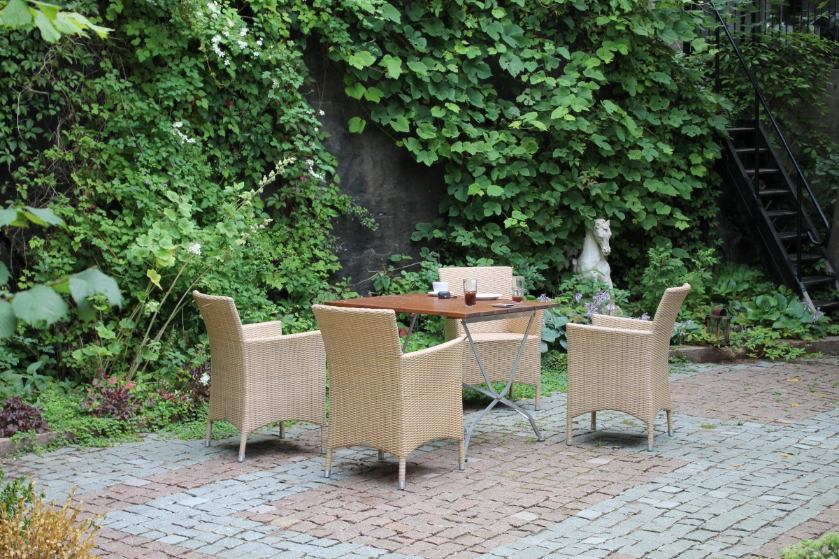 Woven rattan furniture set positioned on a backyard patio with climbers living wall