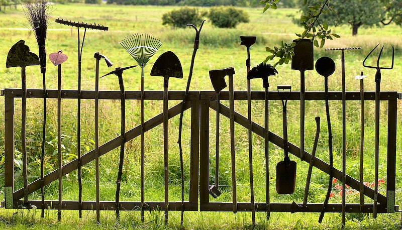DIY garden gate made of old gardening tools, including rakes and shovels