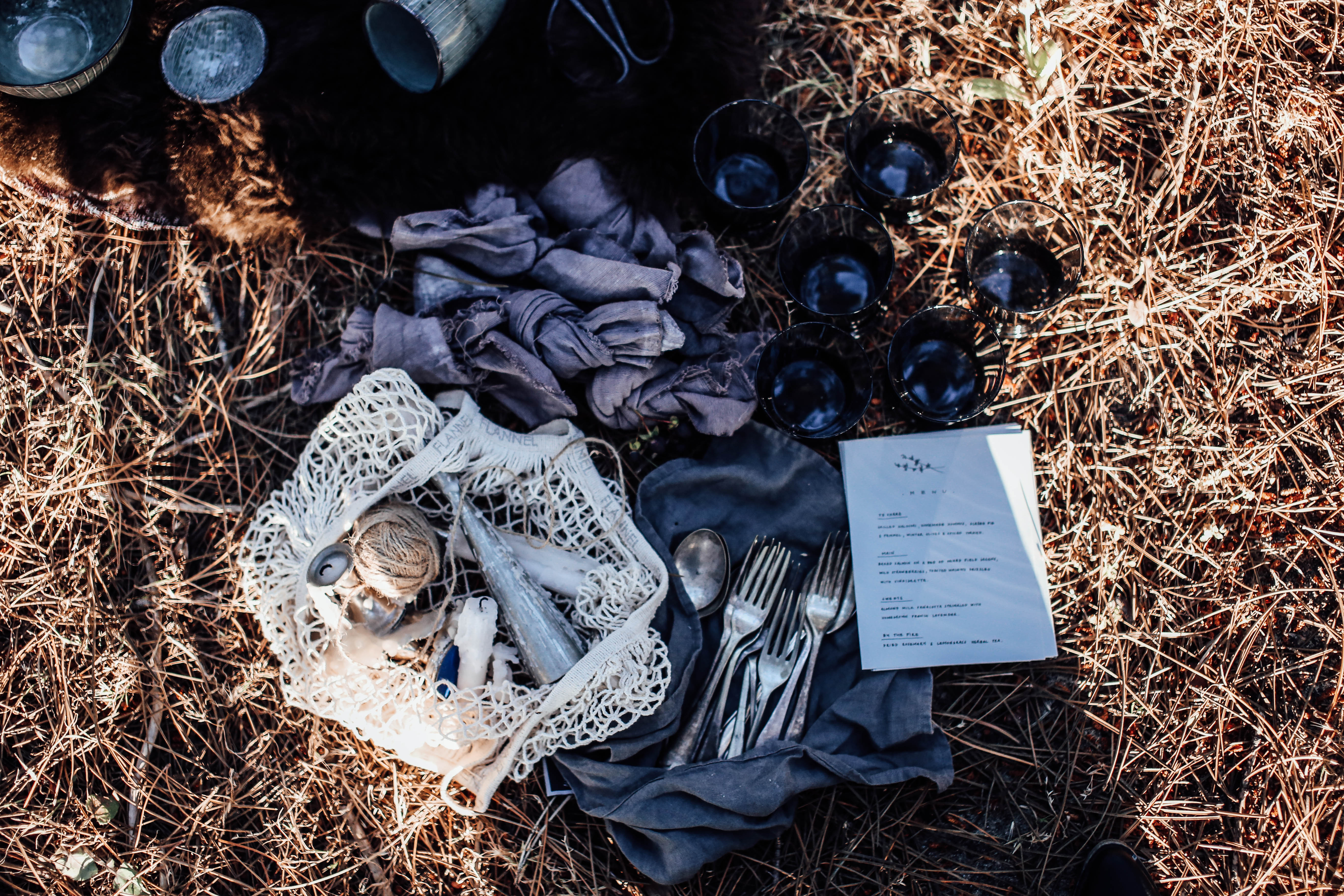 Napkins and reusable bag near cutlery and glasses on grass