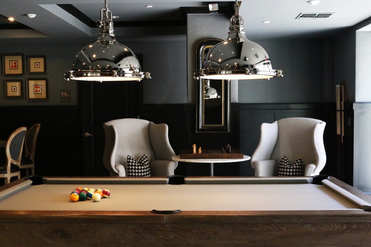 Modern man cave interior with large pendant lighting above a pool table