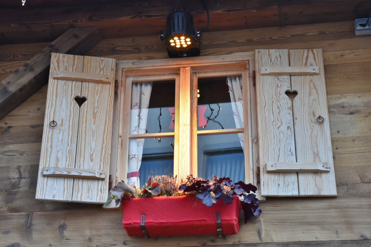 Log cabin window with opened shutters