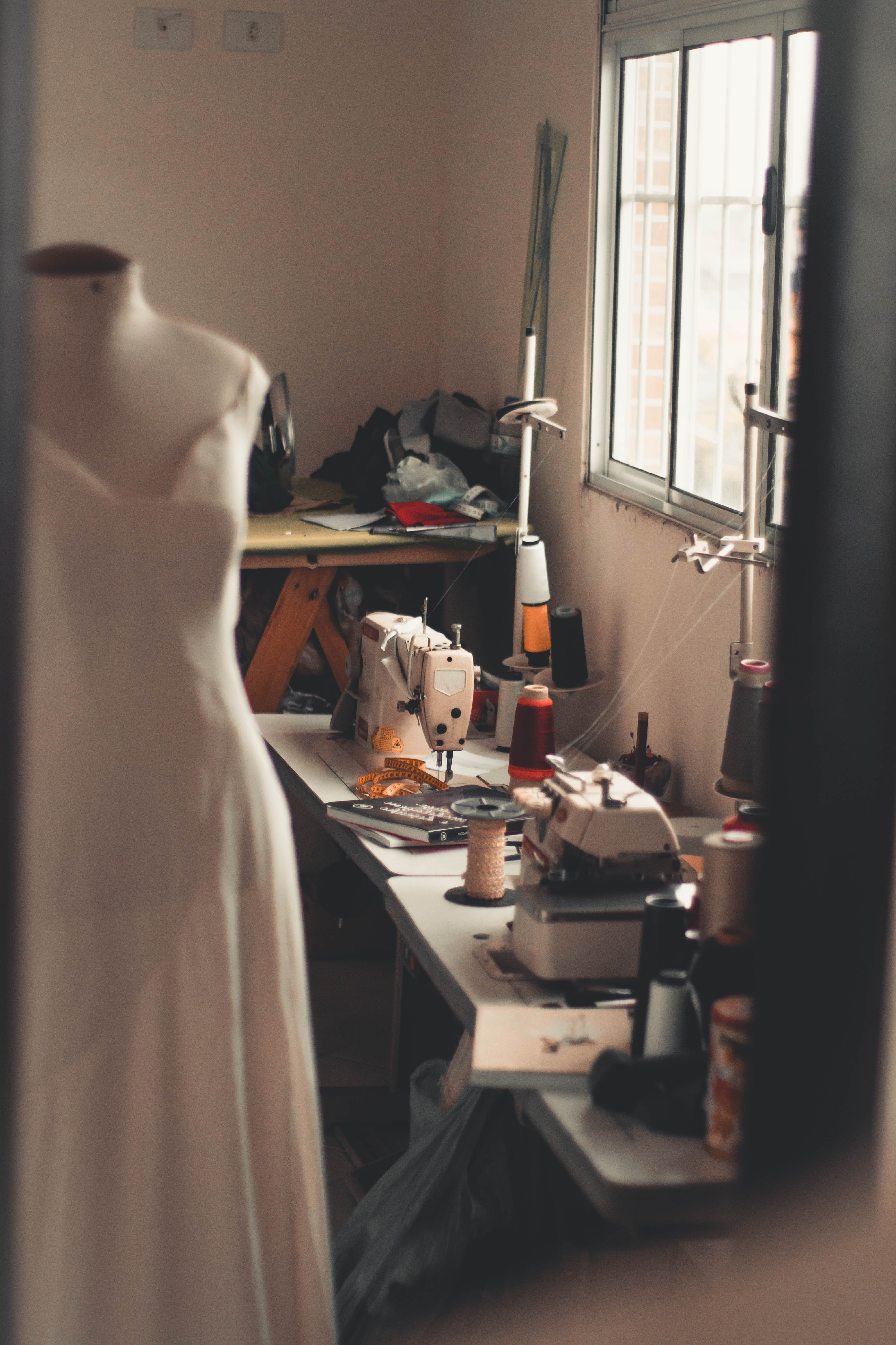 White dress on mannequin beside white sewing machine