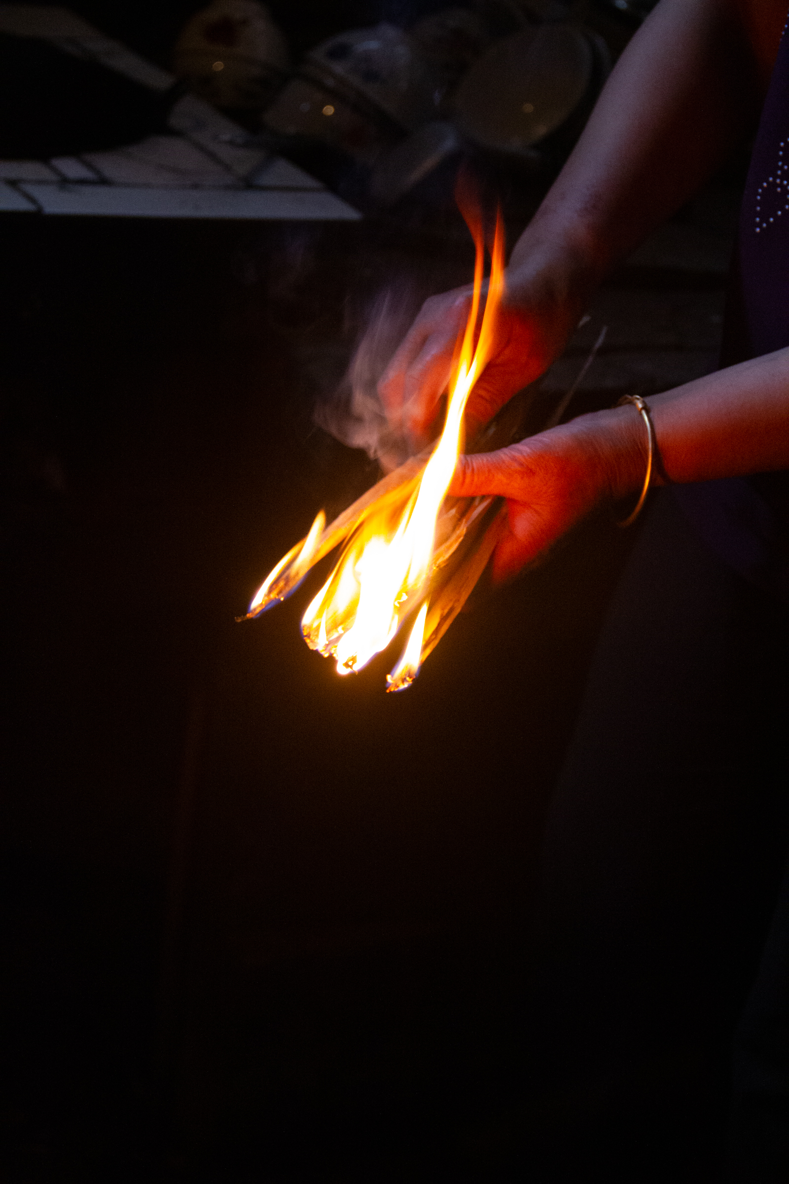 A person holding a burning kindling