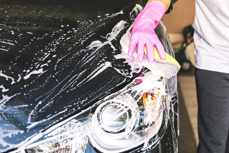 A person washing a car wearing a pink glove