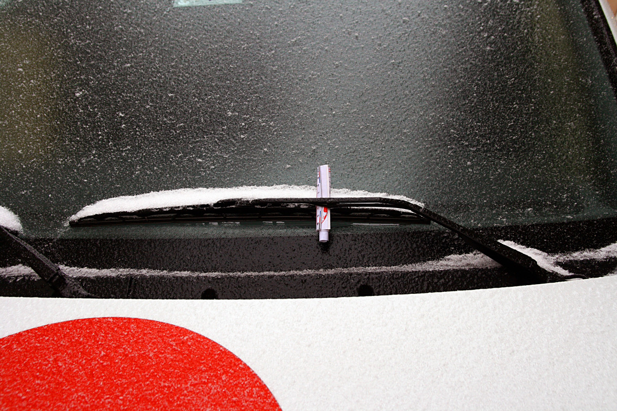 Car windshield wiper covered in snow