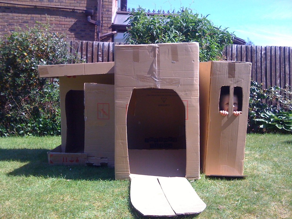 A kid inside a DIY cardboard garden castle