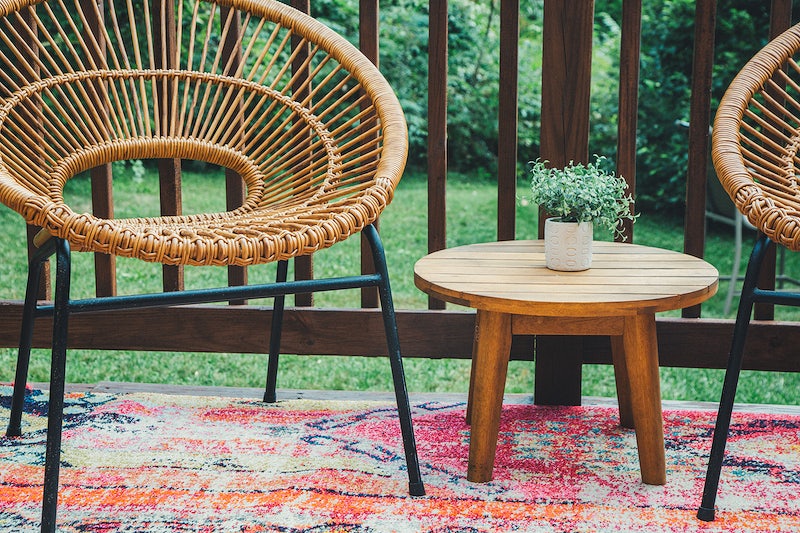 Rattan chairs with mini wooden coffee table in between and an outdoor rug under