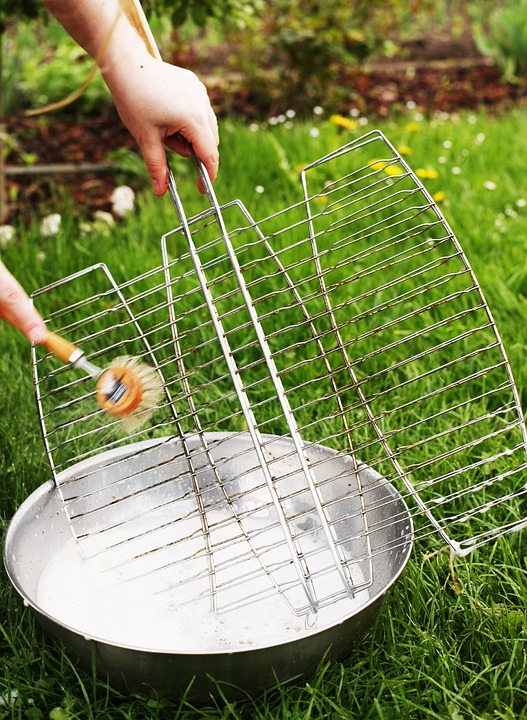 A person cleaning a grill rack with a brush