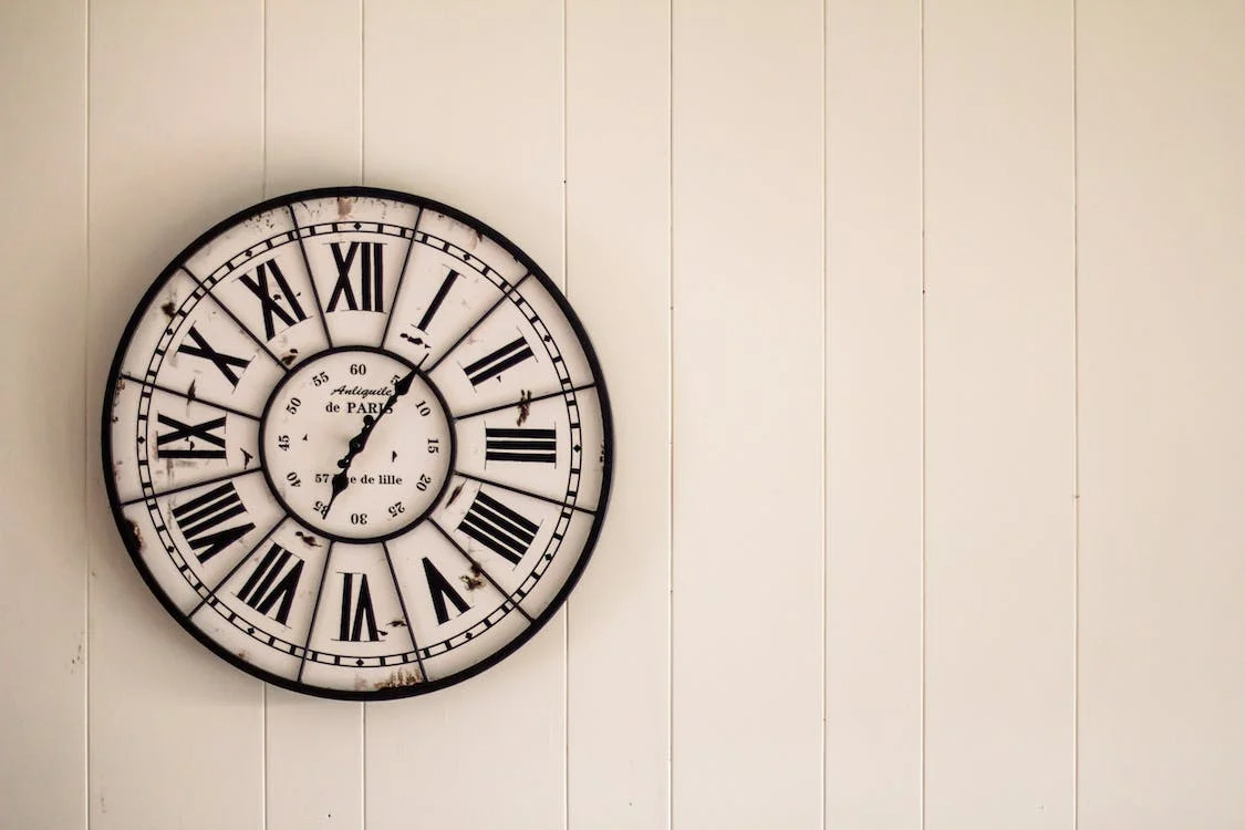 Vintage wall clock installed on a white wooden wall