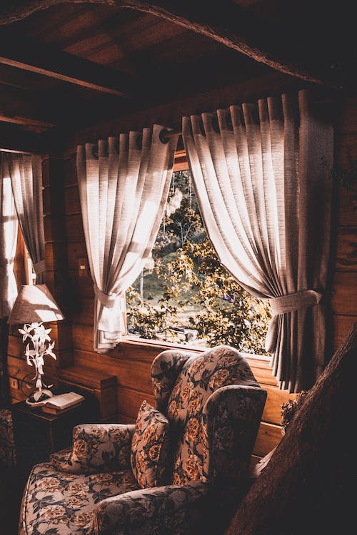 Log cabin with open windows, decorated with curtains