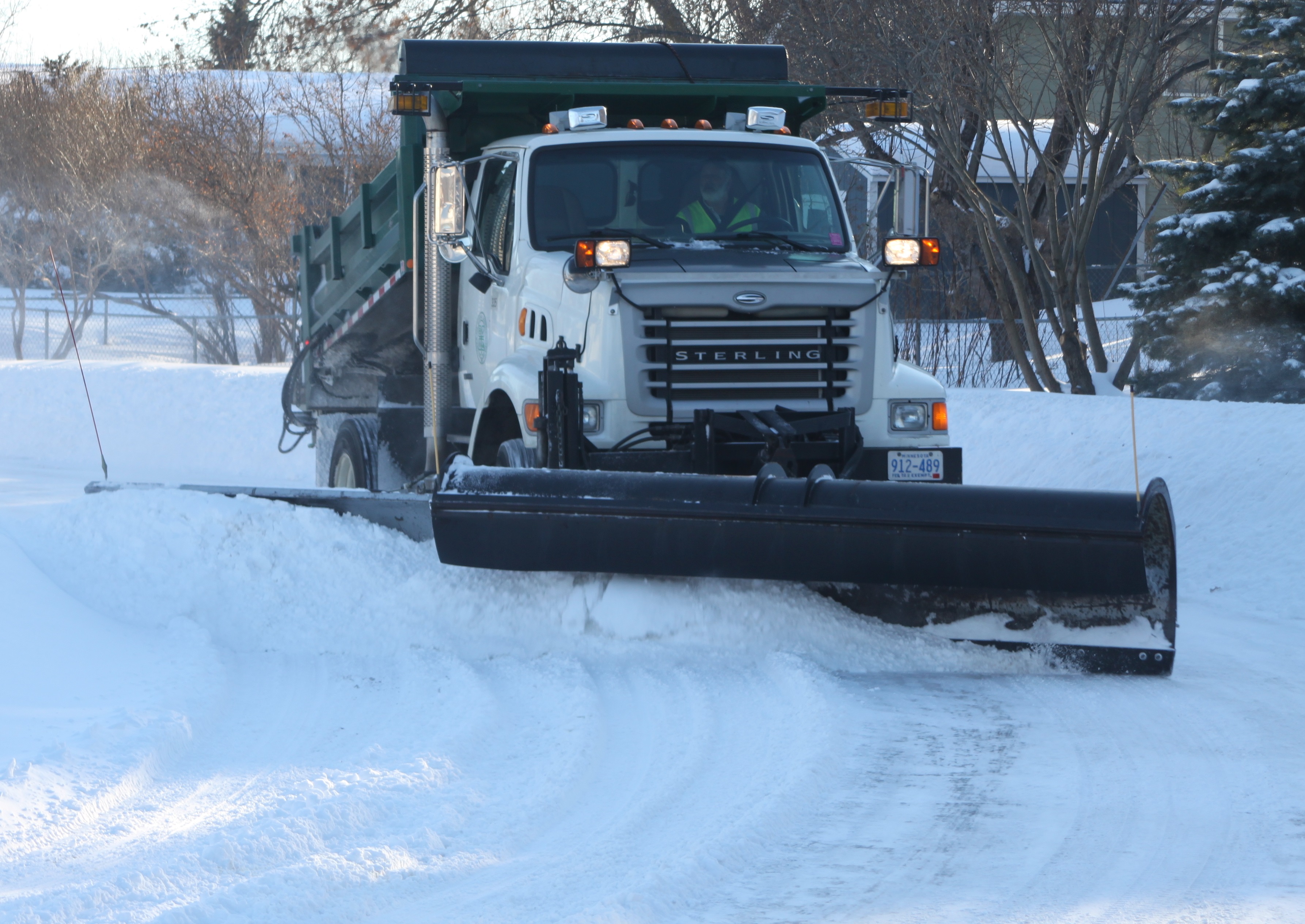 Truck with a large snow plough moving snow on the road