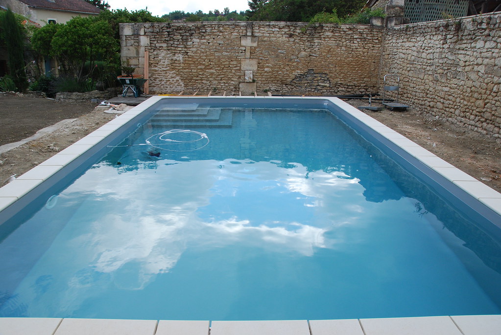 A backyard under construction with blue water swimming pool
