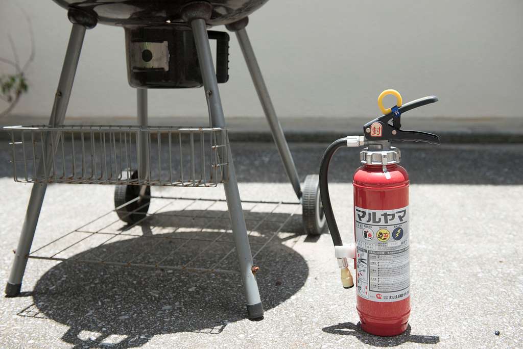 A fire extinguisher sits next to a grill