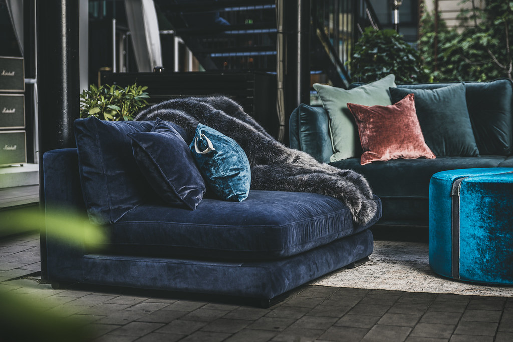 A navy blue velvet sofa adorned with matching navy blue pillows and a soft fur throw.