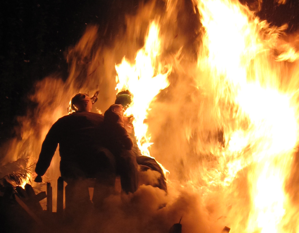 A large bonfire with two figures resembling Guy Fawkes effigies being burned in celebration of Bonfire Night.