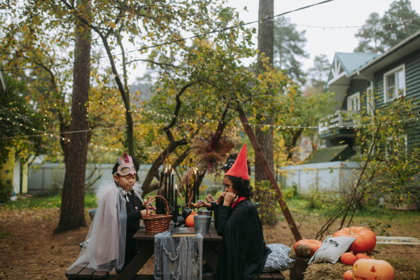 Kids in Halloween costumes eating in the yard.