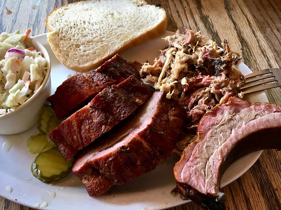 Smoked pork ribs and pulled roast pork served on a plate with a side of coleslaw.